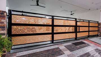 A corridor with patterned decorative screens, a ceiling fan, and a tiled floor.