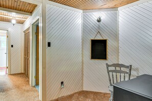 A room with white paneled walls, a wooden ceiling, a small blackboard, and a chair. - Lake Ogemaw Escape: Private Beach & Dock (West Branch)