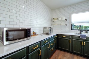 A modern kitchen with white subway tiles, stainless steel appliances, and dark green cabinets. - Steps From Downtown Square! 3-Apt Group Escape (Mountain Home)