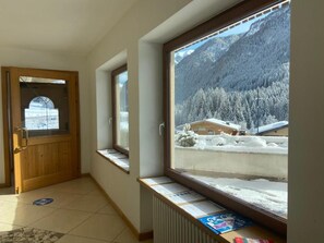 A hallway with a wooden door and windows with a view of snow-covered mountains. - Hotel Pizboè (Mazzin)