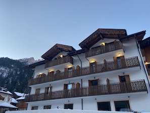 A multi-story building with balconies, likely a hotel or resort, with a mountainous backdrop. - Hotel Pizboè (Mazzin)