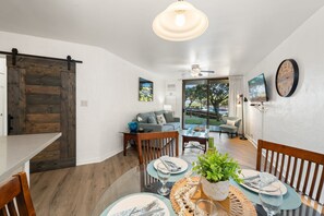 A dining area with a round table, chairs, and a decorative centerpiece. - 1BD Garden View Retreat with AC Near South Maui Beaches- Kauhale Makai 108 (Kihei)