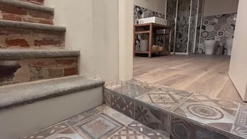 A staircase leading to a room with patterned tiles and a shower area.