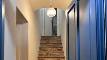 Een trap met een bakstenen muur en een blauwe deur bovenaan.