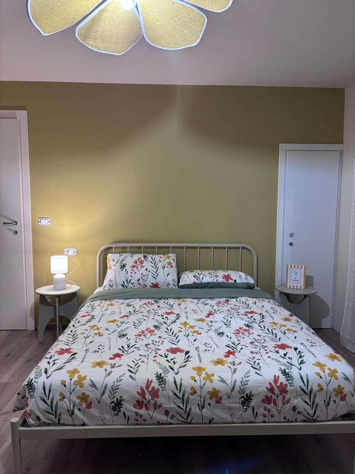 Ein Schlafzimmer mit einem Bett, einem Nachttisch mit Lampe sowie einer Tür.