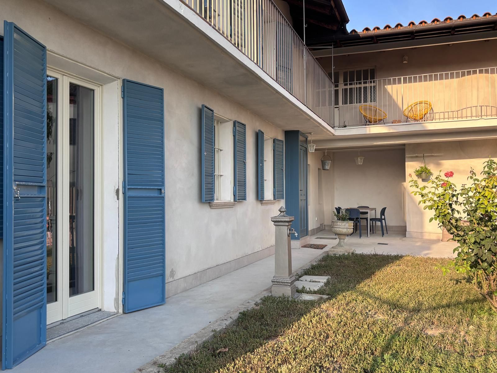 A residential building with a covered patio, a dining area, and a small garden.