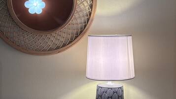 Un miroir mural orné d’un motif géométrique, une lampe au design inspiré des feuilles et une console blanche.