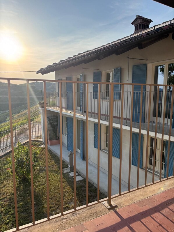 A multi-story building with balconies, a view of a hilly landscape, and a clear sky.
