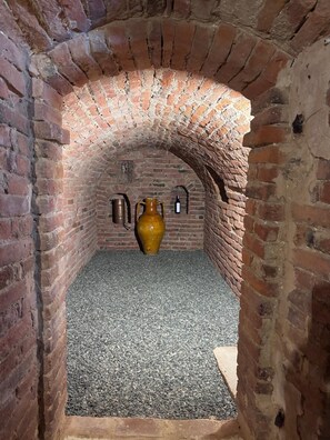 An arched brick corridor with a large vase and two wall-mounted objects.
