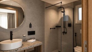 A modern bathroom with a large round mirror, a granite countertop, a white sink, and a glass-enclosed shower area. - Arena Beach Resort & Spa (Red Sea Governorate)