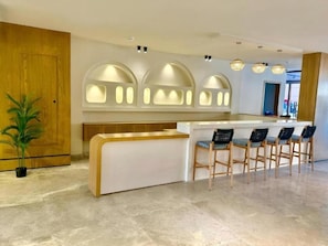 A modern kitchen with a bar area, wooden cabinets, and a potted plant. - Arena Beach Resort & Spa (Red Sea Governorate)