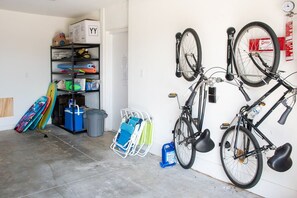Un garatge amb bicicletes, taules de surf i productes de neteja.