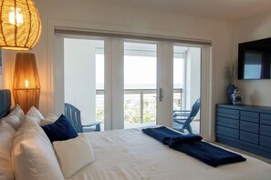 Ein Hotelzimmer mit einem Bett, einem großen Fenster, einem Balkon und einem an der Wand befestigten Fernseher.