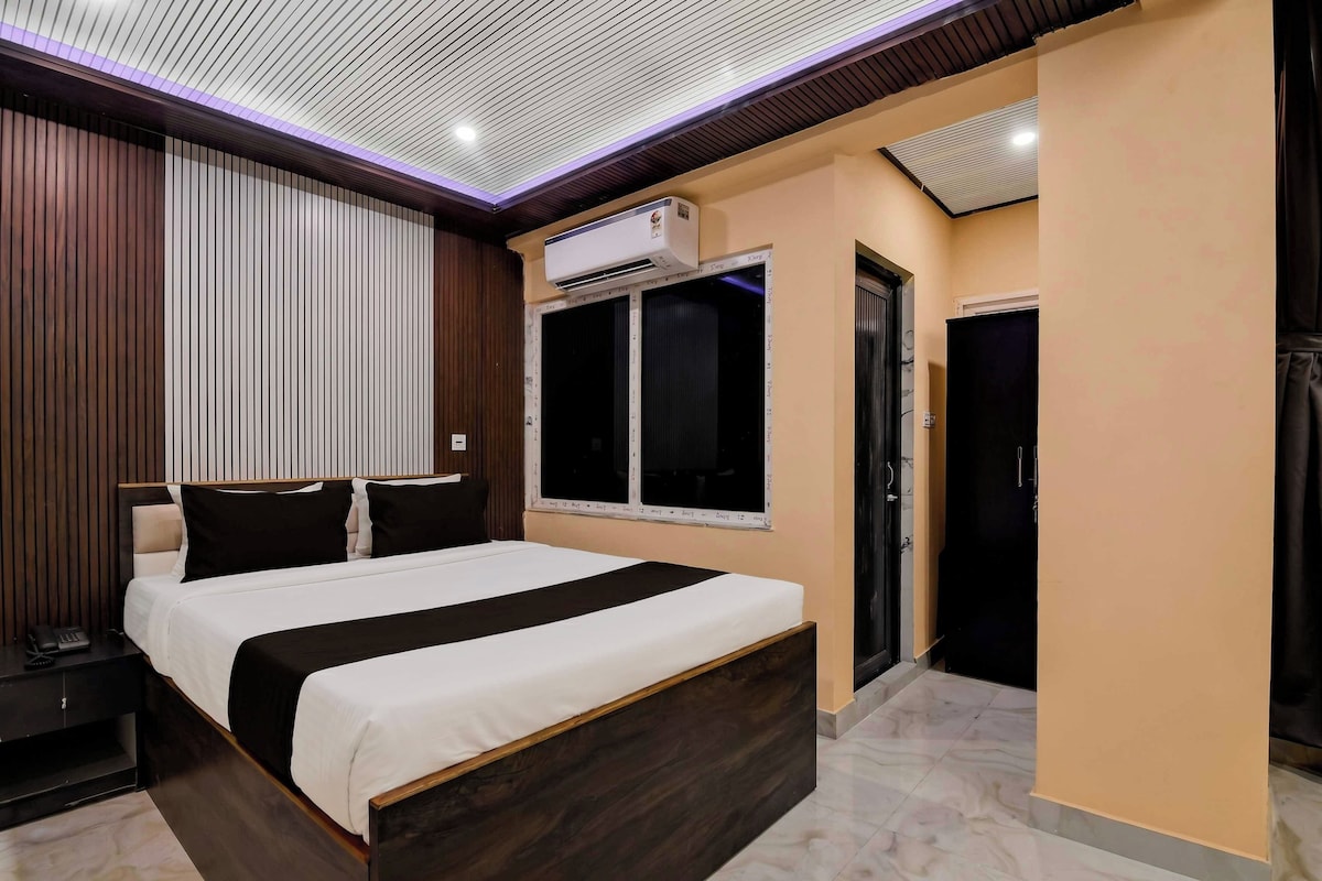 Un dormitorio moderno con una cama grande, una mesita de noche, un aire acondicionado de pared y una ventana con persianas.