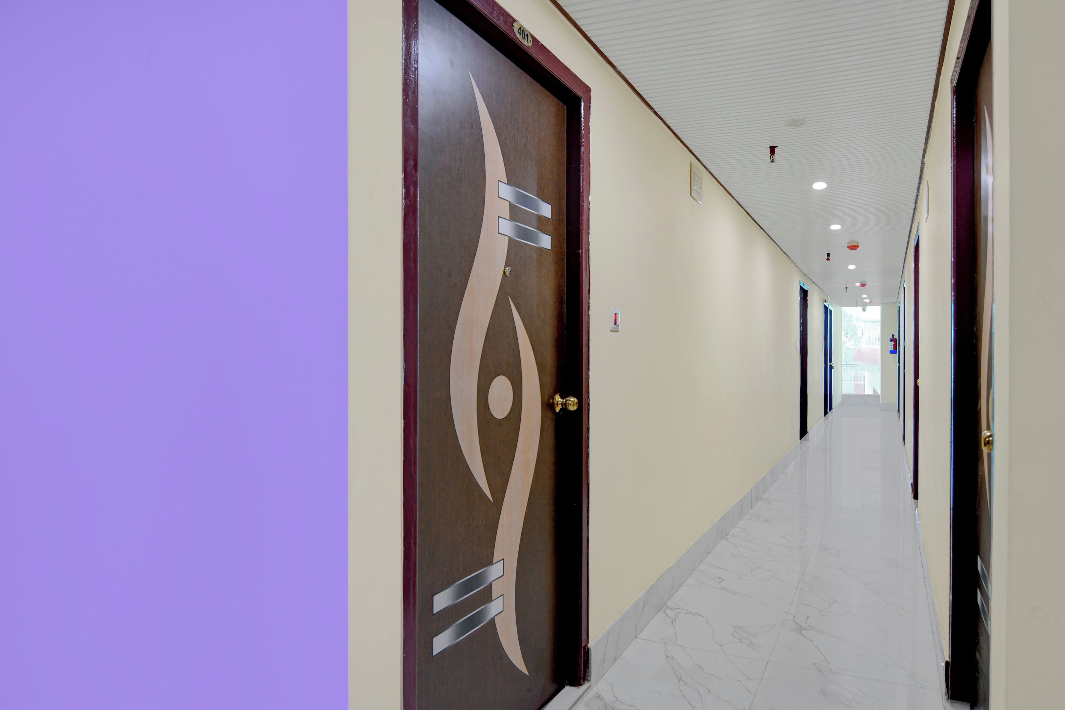 A long, narrow hallway with marble flooring and doors on one side.