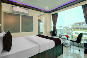 Una habitación de hotel con cama, escritorio, silla y vistas a la ciudad.
