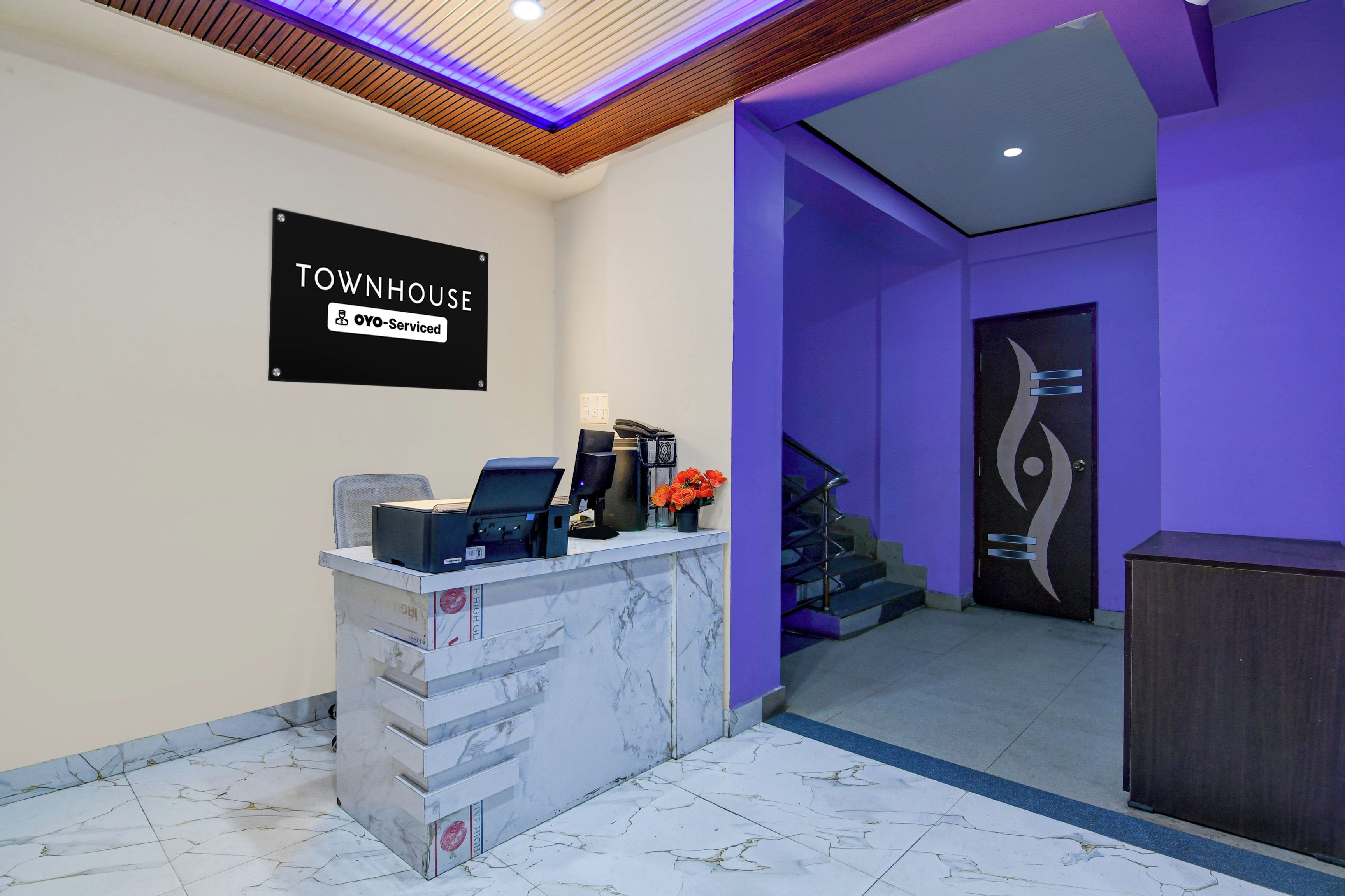 Ein Empfangstresen mit einem Schild, auf dem 'TOWNHOUSE YOYO-Serviced' steht, in einer Lobby mit violetten Wänden und modernem Design.