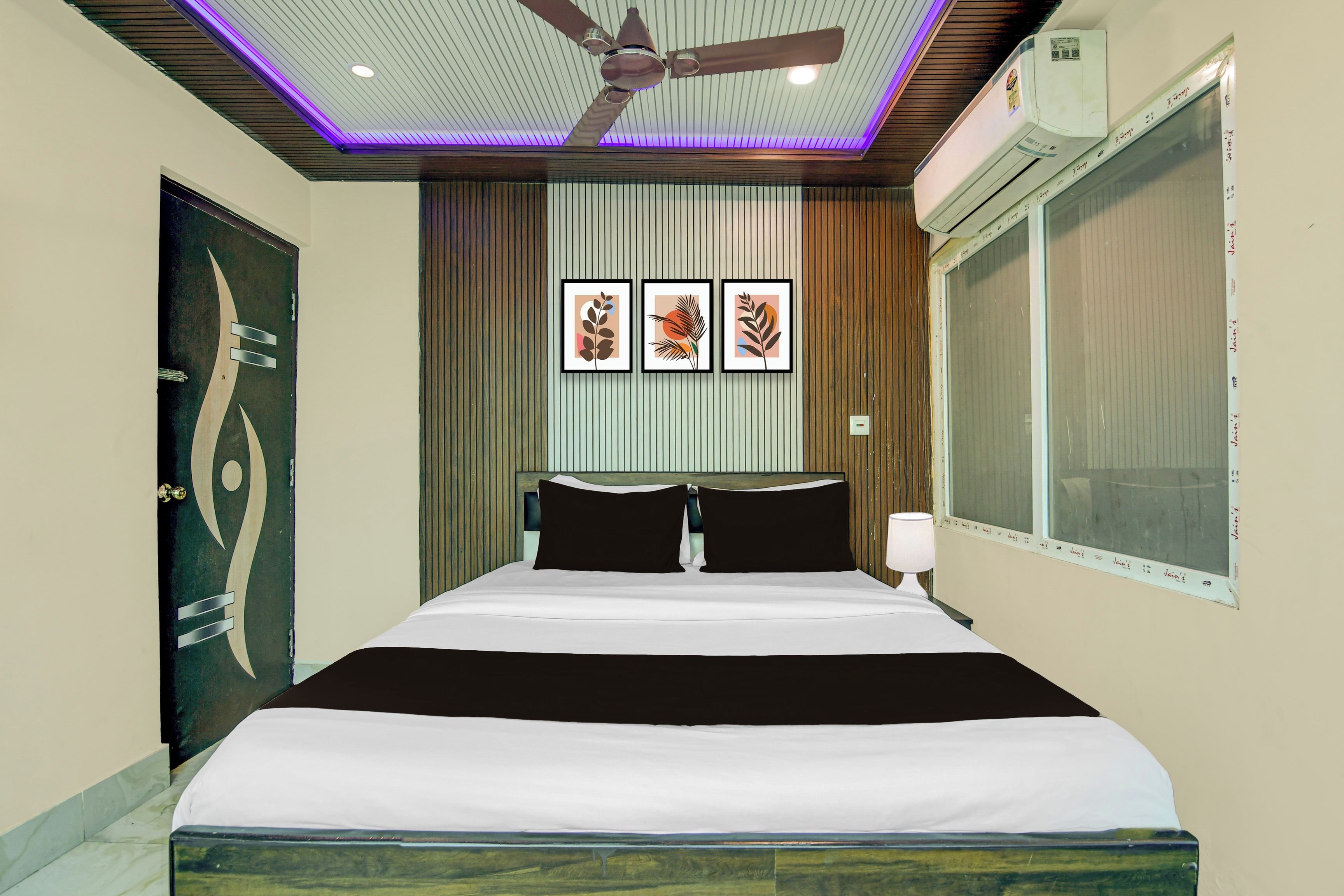 Une chambre à coucher avec un lit, un ventilateur de plafond, une fenêtre et des œuvres d’art murales.
