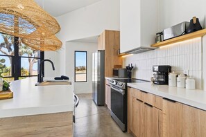Eine moderne Küche mit einer großen Kochinsel, Edelstahlgeräten und Blick ins Freie.