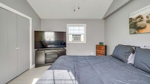 Ein Schlafzimmer mit Bett, Fernseher, Schminktisch und Fenster.
