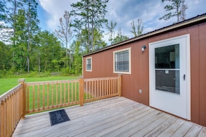 A wooden deck with a welcome mat, a door, and a small window with blinds.