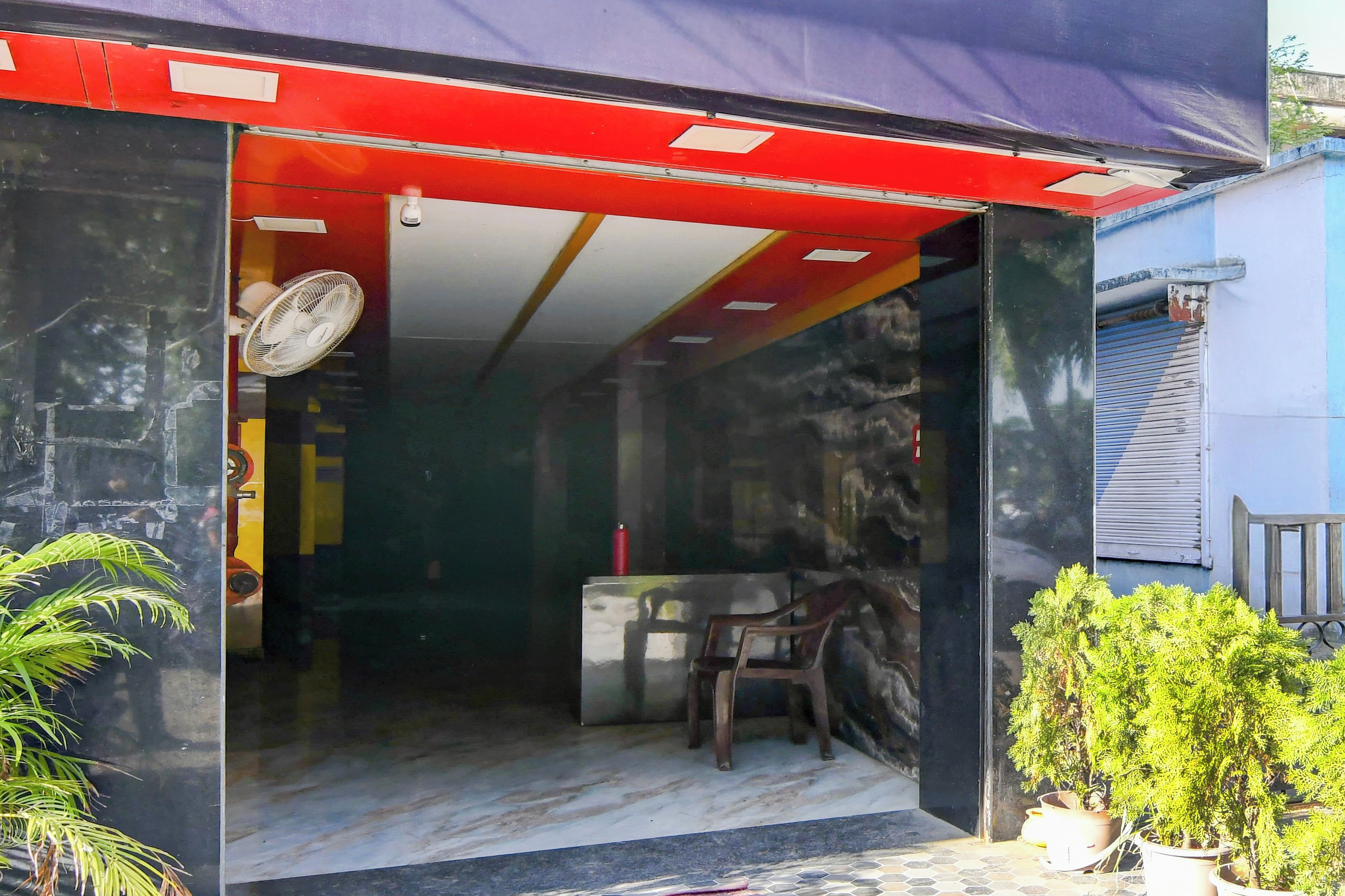A room with a red awning, a fan, a chair, and a small table.