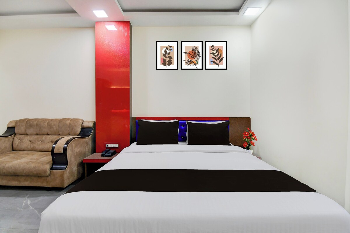 Una habitación de hotel con una cama, un sofá, una mesita de noche, un teléfono y tres cuadros en la pared.