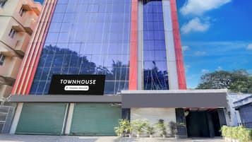 A modern building with a large glass facade, a sign reading 'TOWNHOUSE Company-Serviced', and a gated entrance.