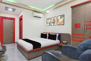 Habitación de hotel con cama, armario, escritorio con teléfono y una silla.