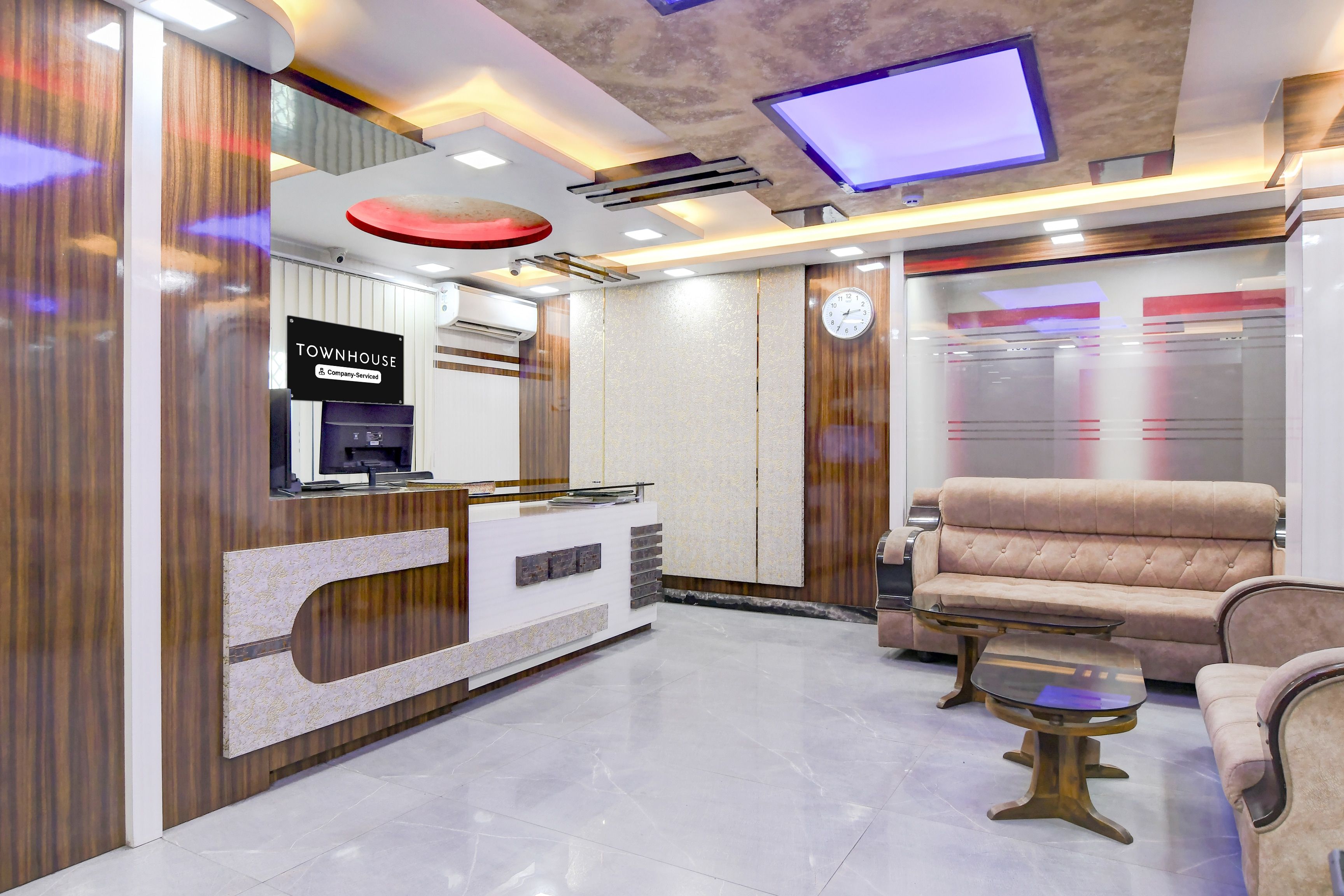 A reception area with a modern design, including a reception desk, a sofa, and a television screen.