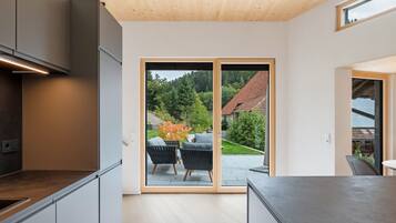 A modern kitchen with a sliding glass door leading to an outdoor seating area with two chairs.