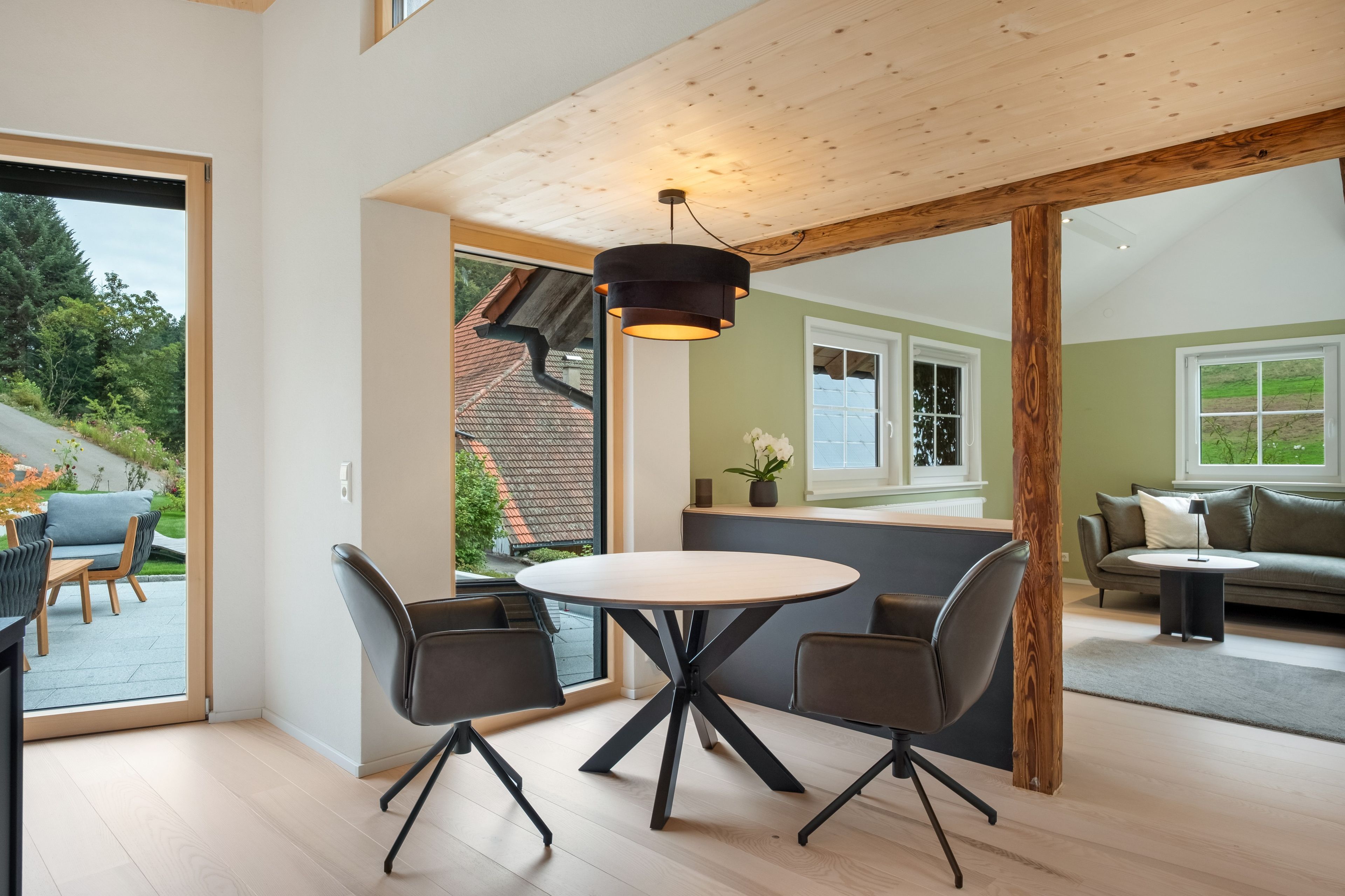 Un espace de vie à aire ouverte comprenant une table à manger, des chaises et une vue sur l’extérieur.
