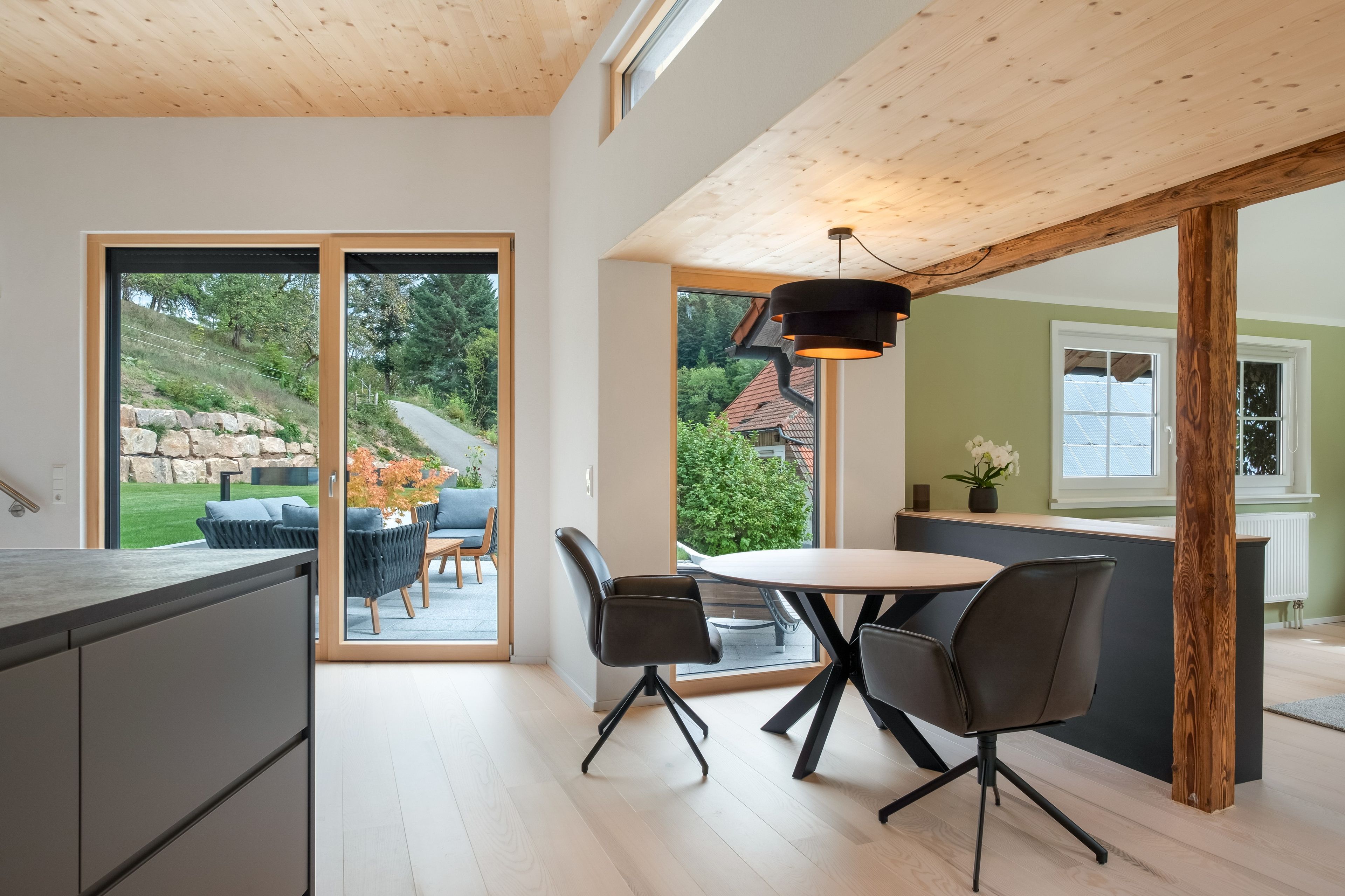 Una cocina moderna con comedor, ventanas amplias y vistas al exterior.