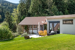 A modern house with a tiled roof, a covered porch, and a well-maintained lawn.