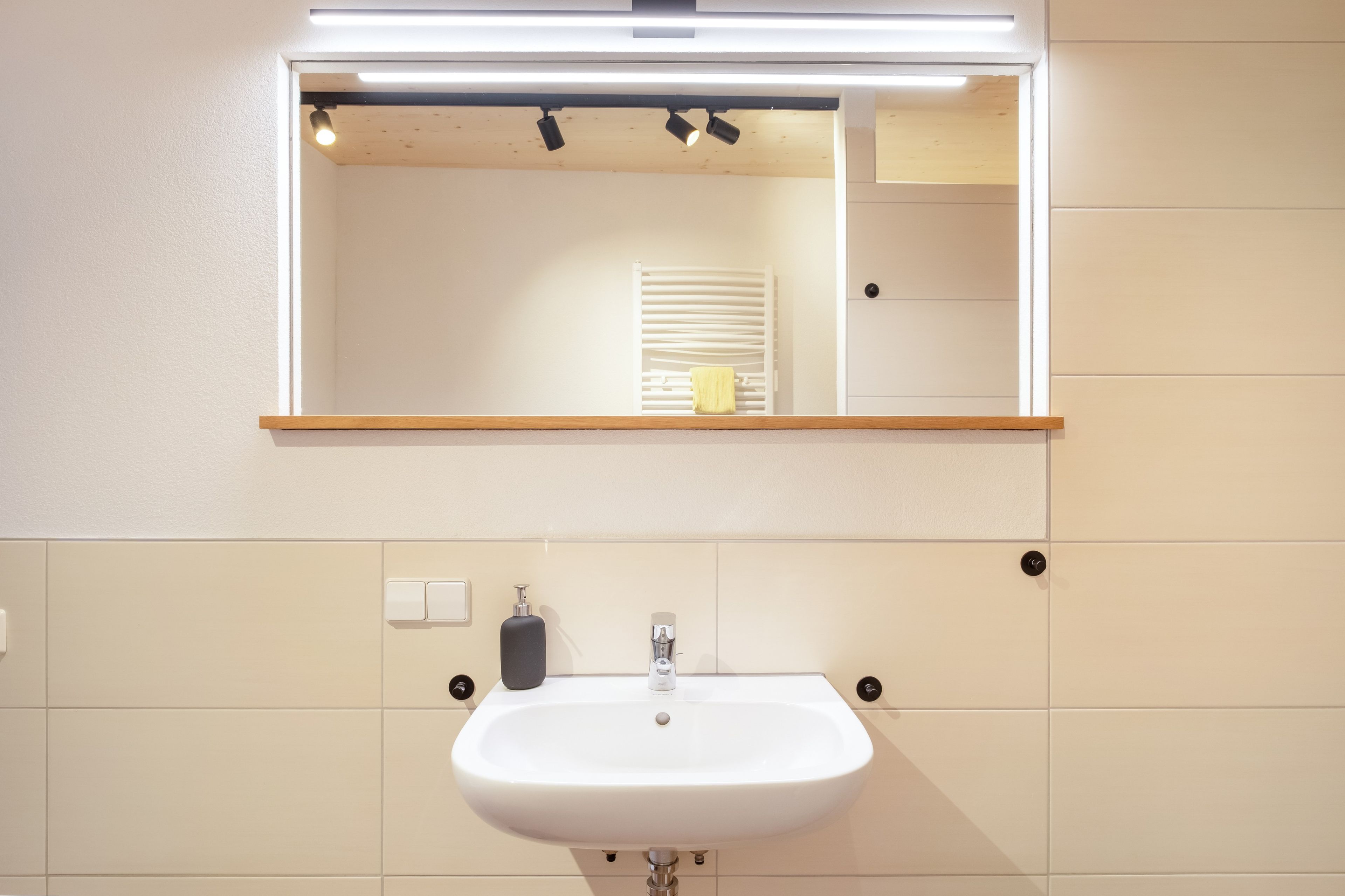 A bathroom with a white sink, a mirror with a wooden frame, and a towel hanging on a towel rack.