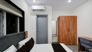 Ein modernes Hotelzimmer mit einem Bett, einem Kleiderschrank, einem Schreibtisch und einer Klimaanlage.