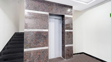 Un pasillo con pared de mármol, una puerta y una escalera.