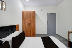 A hotel room with a bed, a wardrobe, and a door. - Townhouse Oak L B Nagar Metro Station (Hyderabad)