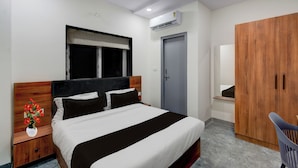 Ein Hotelzimmer mit Bett, Kleiderschrank, Schreibtisch und Fenster.