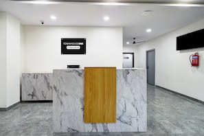 A reception desk with a marble top, a wooden panel, and a sign indicating it is company-serviced. - Townhouse Oak L B Nagar Metro Station (Hyderabad)