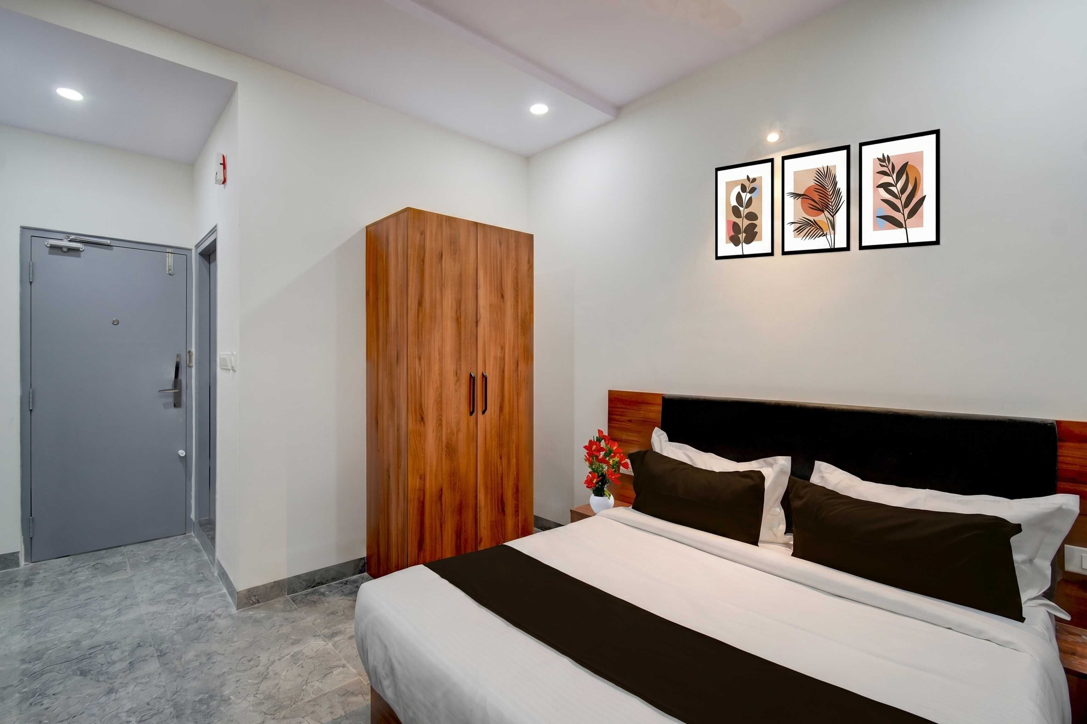 Ein Hotelzimmer mit einem Bett, einem Kleiderschrank, einer Tür und drei gerahmten Bildern an der Wand.