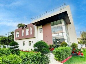 A modern hotel building with a flat facade, large windows, and a sign indicating it is a hotel. - Deluxe Hotel Madhuvan & Lawn (Lucknow)