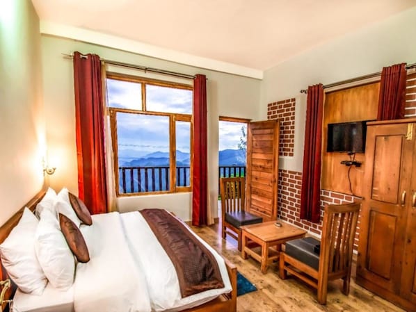 A bedroom with a bed, a desk, a chair, and a TV. - LA Riqueza Kanatal (Tehri)