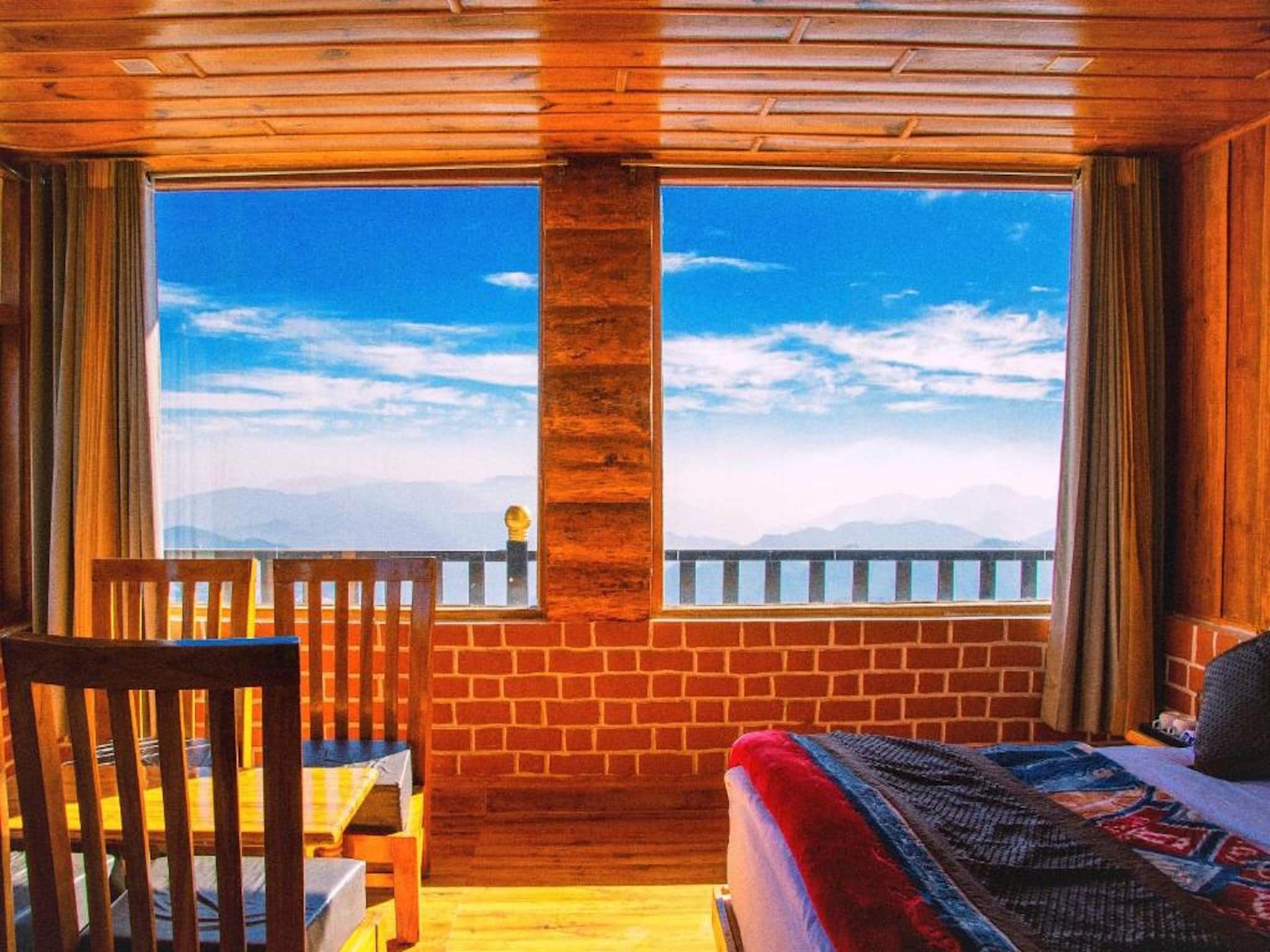 Une pièce avec une grande fenêtre, un lit, une chaise et un plafond en bois.