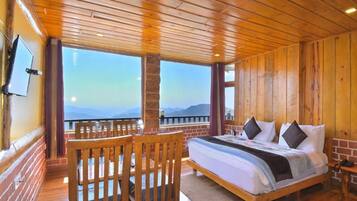 Habitación de cabaña de madera con cama, televisión y balcón con vistas.
