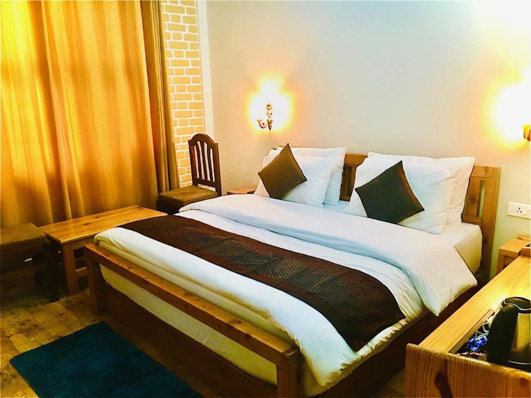 Una habitación de hotel con una cama de madera, una mesita de noche, una silla y una lámpara.