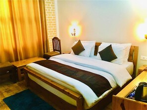 A hotel room with a wooden bed, a nightstand, a chair, and a lamp.