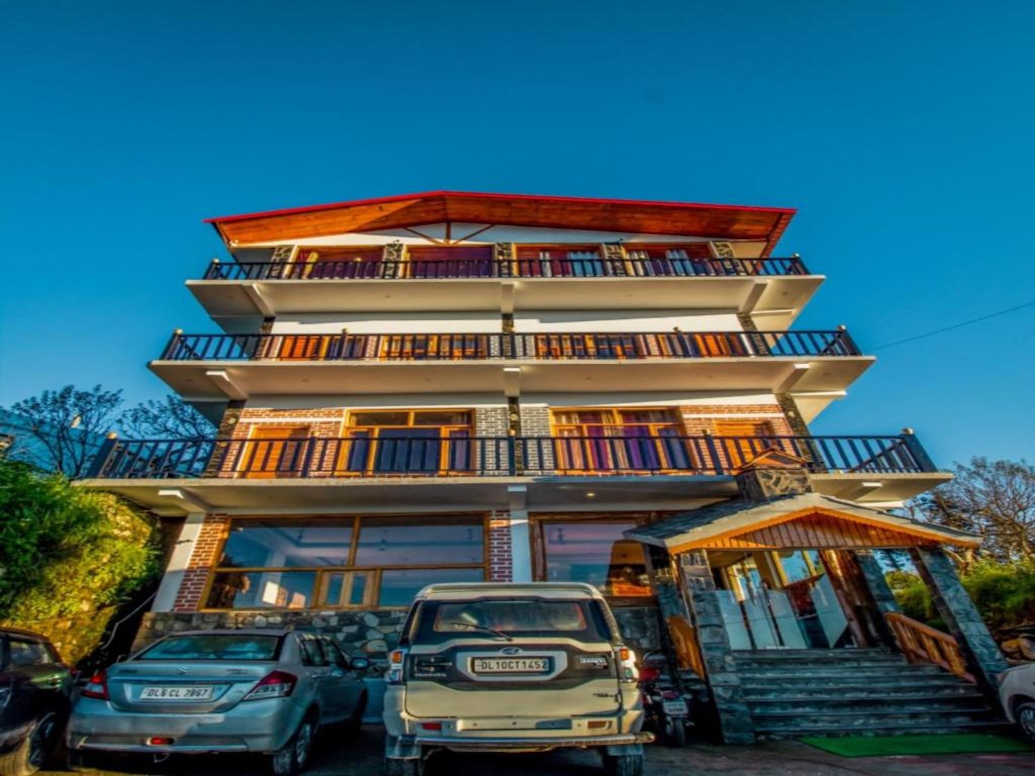 A multi-story building with balconies, a garage, and a staircase leading to the entrance.