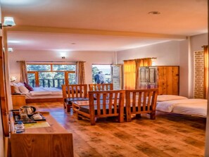 A cozy room with a wooden floor, a bed, a table with chairs, and a window with curtains.