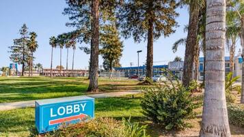 A sign labeled 'LOBBY' in a grassy area with trees and a building in the background.